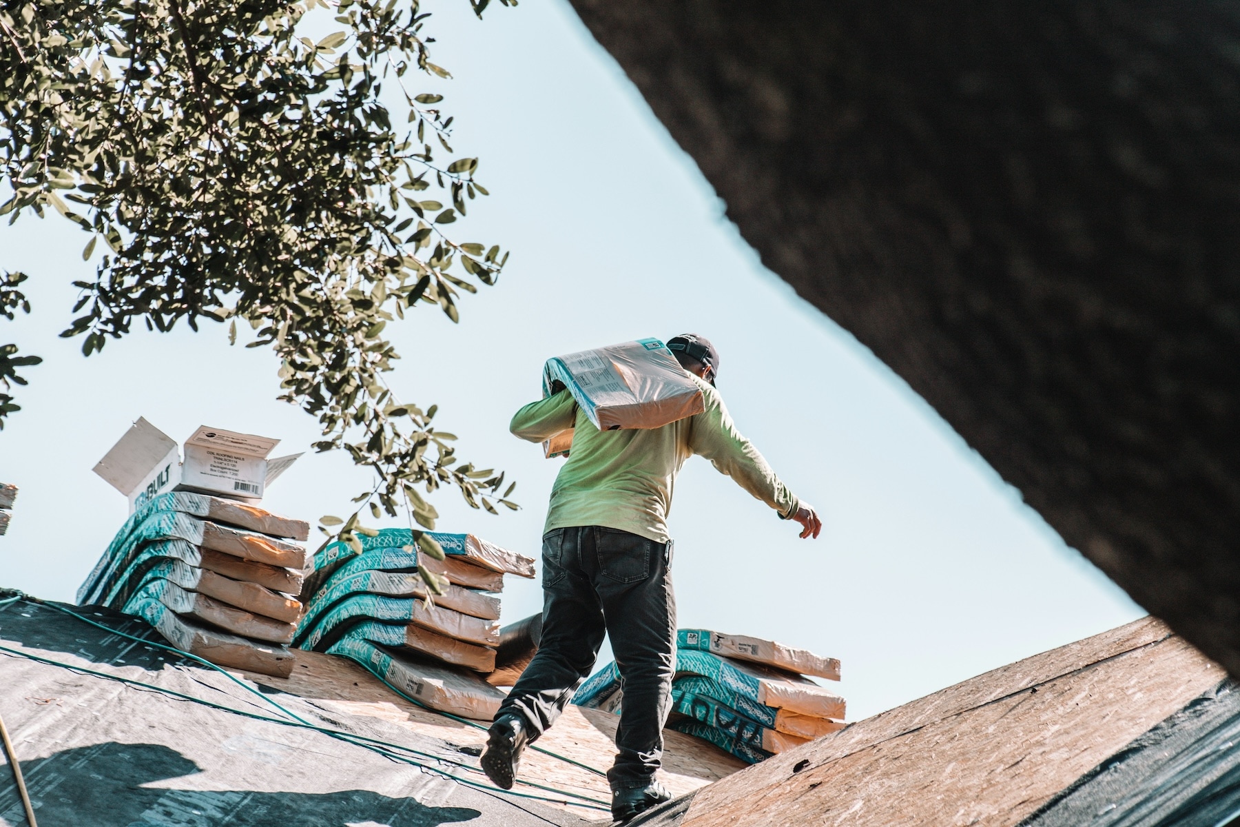 Roofing crew carrying bundles of architectural shingles up to a residential roof during an installation project, representing the hands-on service specificity that structured schema markup communicates to AI search engines