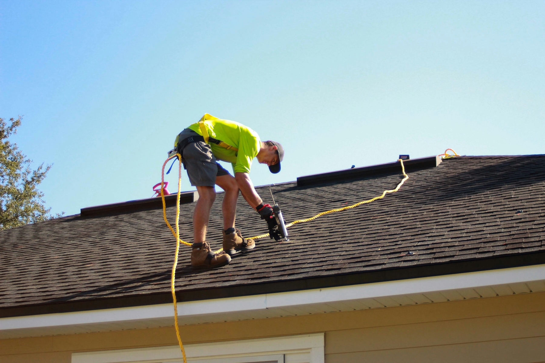 Experienced roofing contractor installing asphalt shingles on a residential roof — the kind of documented service work that AI search engines cite when homeowners ask for a trusted local roofer