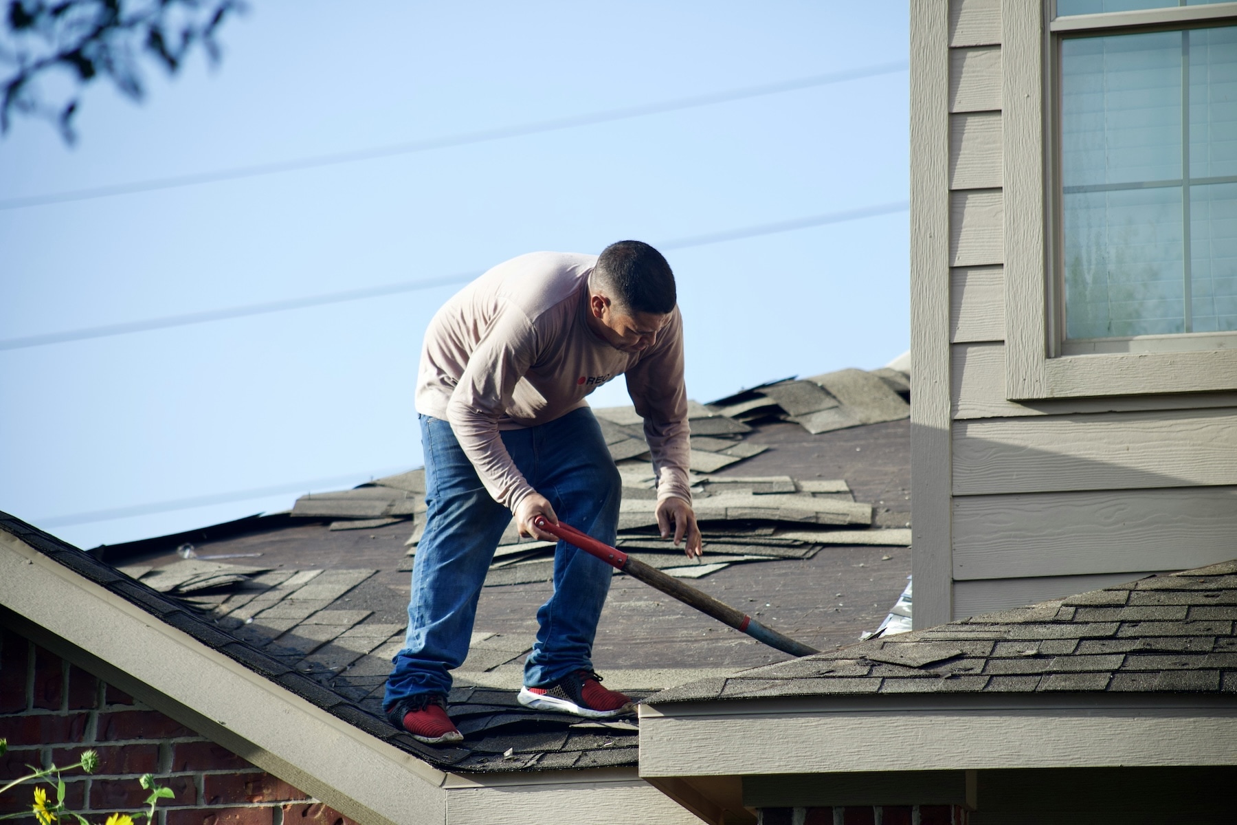 Roofing contractor removing damaged shingles during a full roof replacement, the type of specific project documentation and service history that builds AI search entity signals for established roofing companies